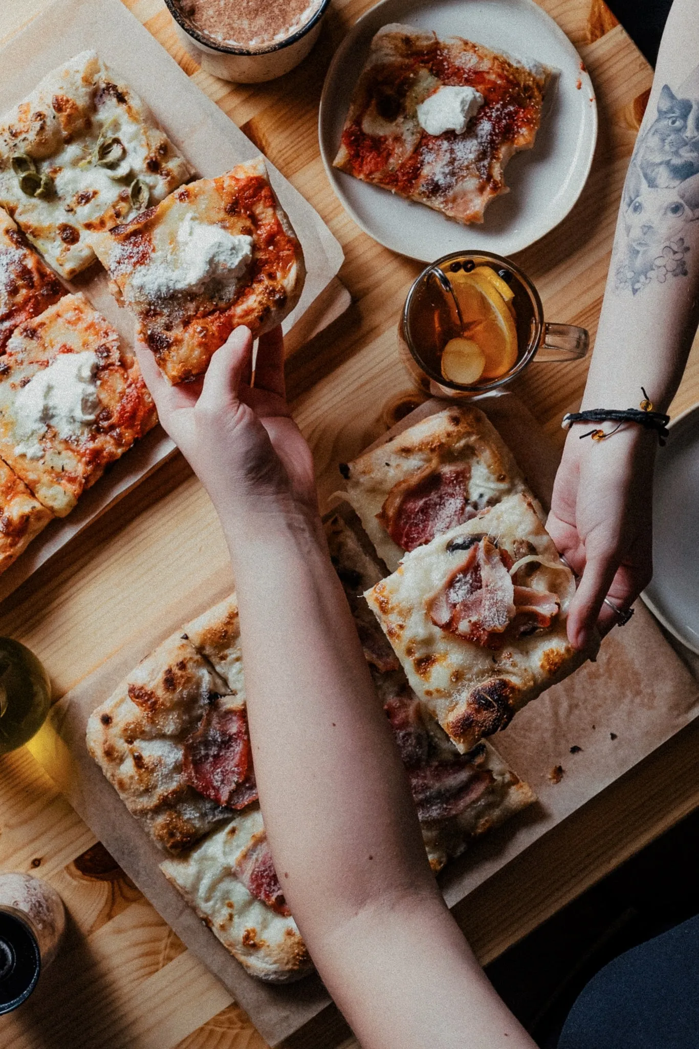 Zdjęcie uniesionych pizz na tle zastawionego stołu